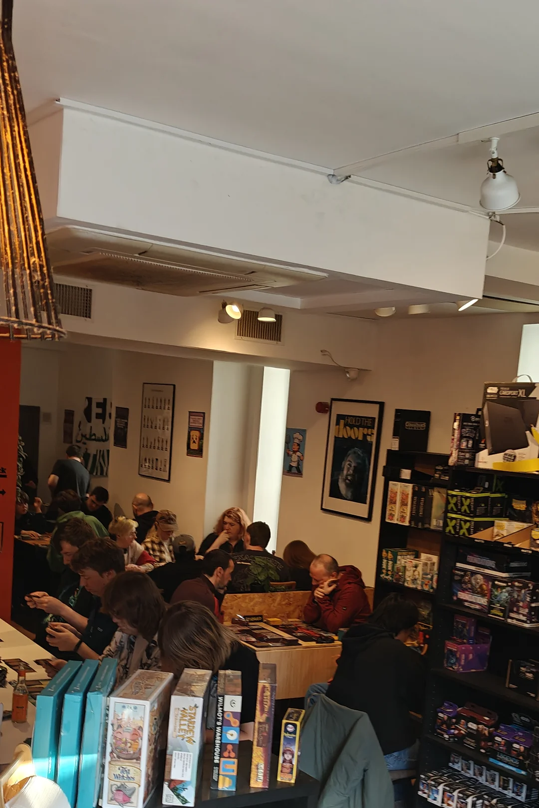 Inside Board & Brewed — customers playing board games beside the game shelves