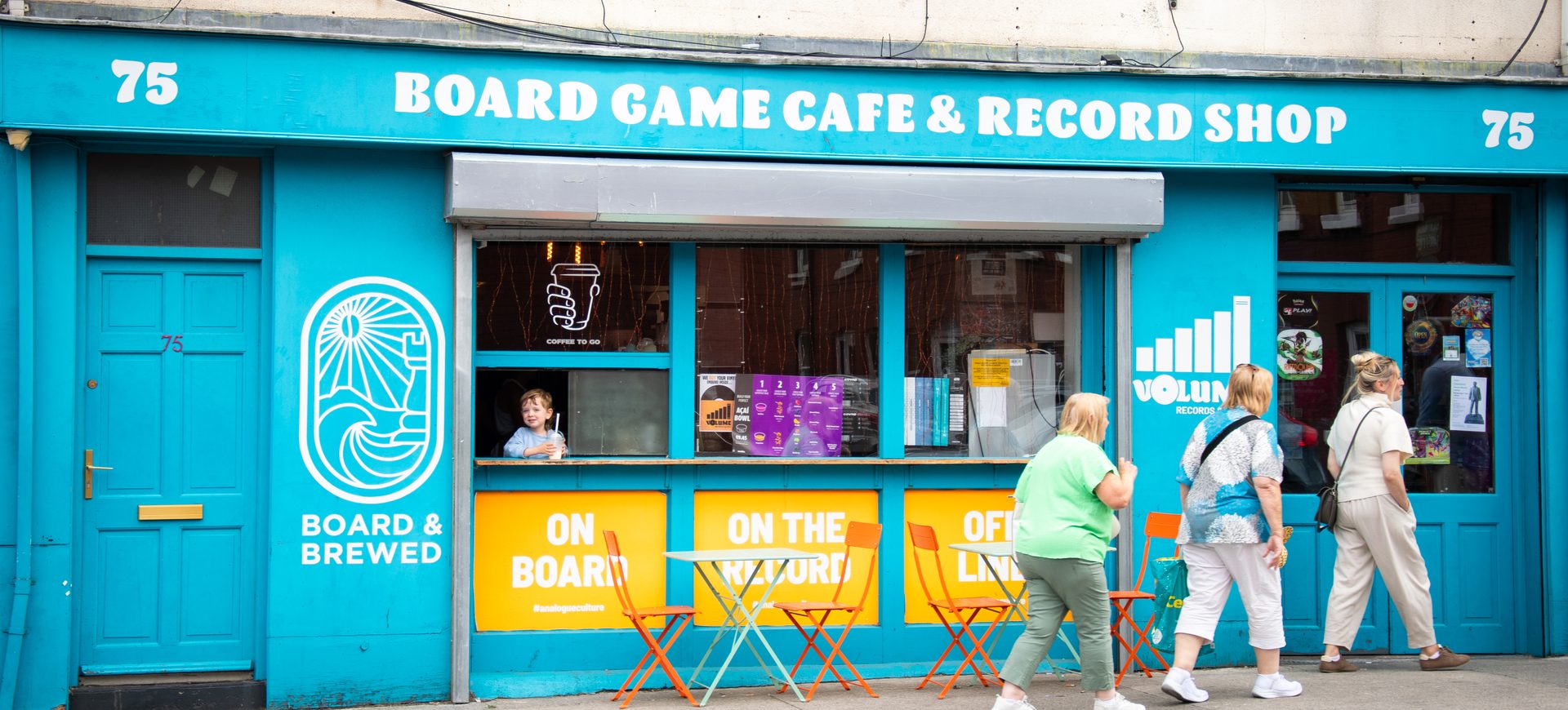 People walking past the blue Board & Brewed shopfront, 75 York Road, Dún Laoghaire